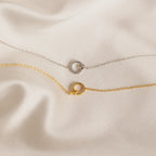 The Pave Interlocking Necklace, perfect unity or bridal jewelry, is elegantly displayed on smooth cream satin fabric.