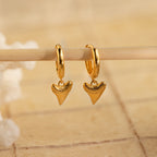 Add edge to your beach look with Shark Tooth Huggies—gold hoop earrings featuring shark tooth-shaped pendants. Bold and stylish, they stand out against any neutral backdrop.
