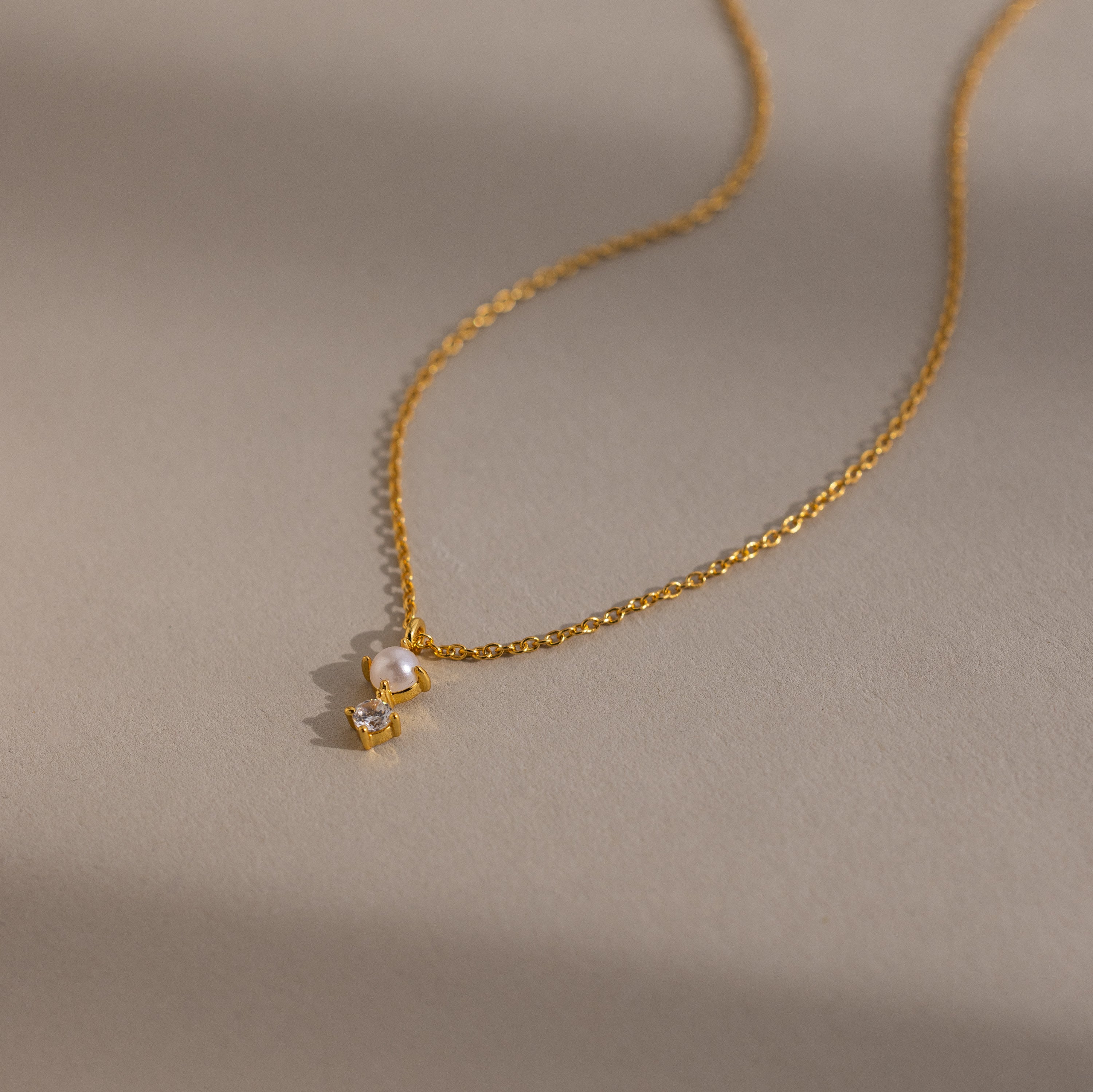The Pearl Diamond Drop Necklace in 18K Gold features a small pearl and diamond pendant, perfect for bridal jewelry, shown on a neutral background.