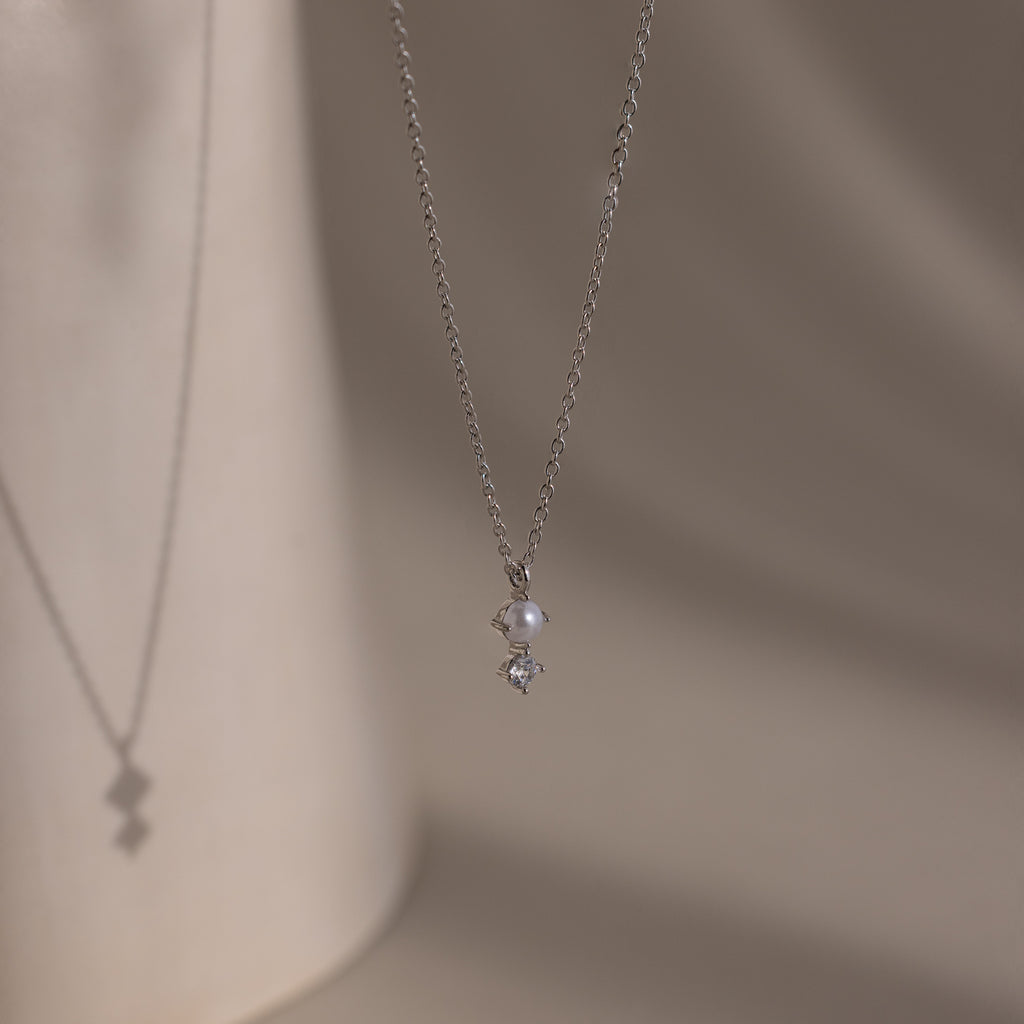 The Pearl Diamond Drop Necklace features a small pearl and diamond pendant, making it an elegant bridal jewelry choice.