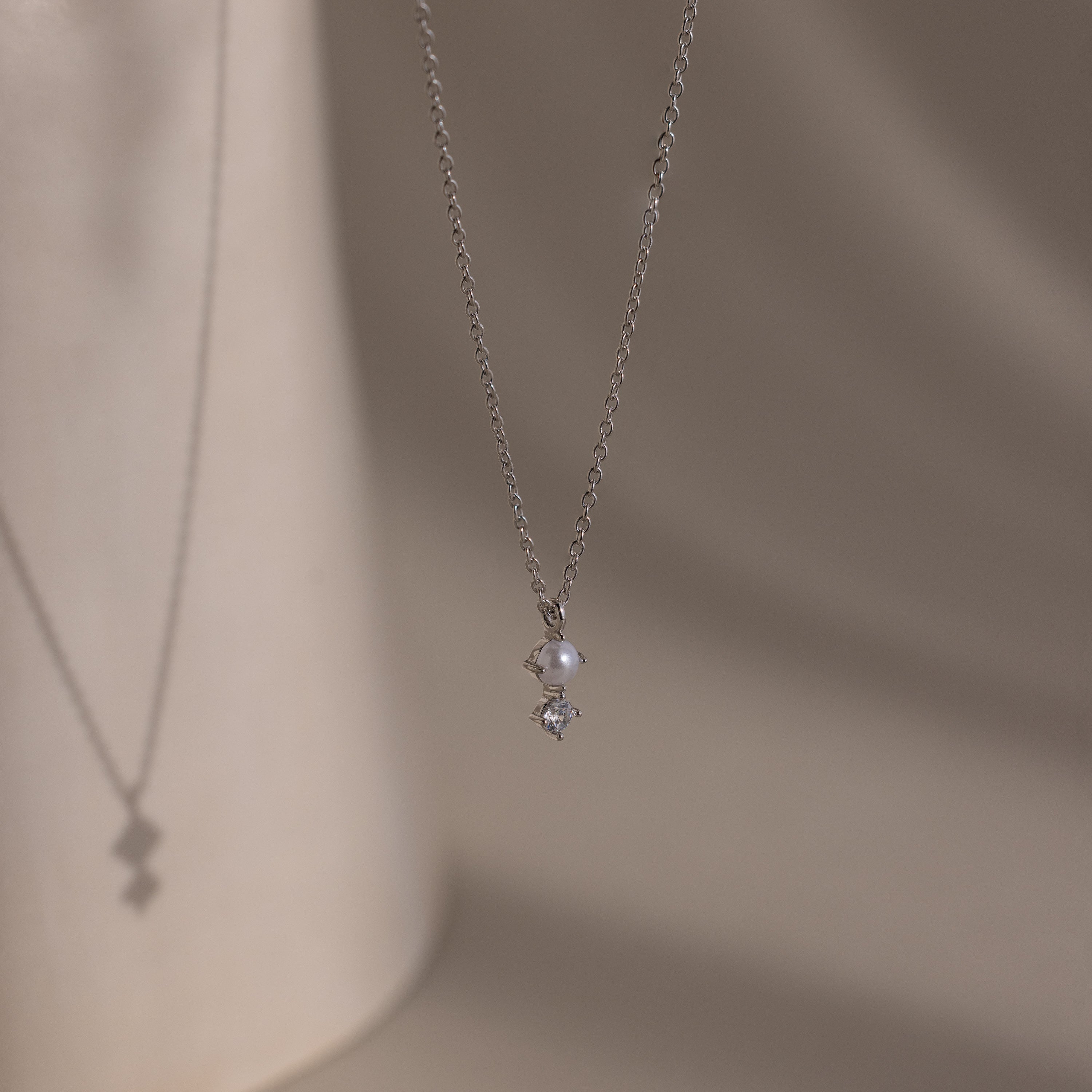The Pearl Diamond Drop Necklace features a small pearl and diamond pendant, making it an elegant bridal jewelry choice.