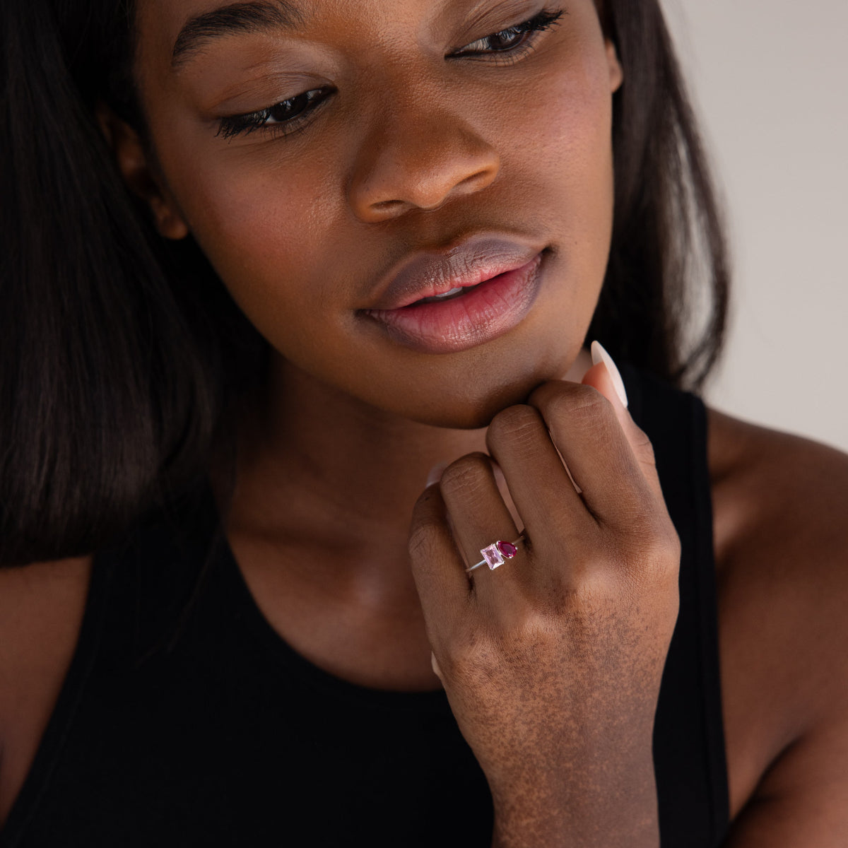 A woman in a black top looks down, highlighting the Toi et Moi Birthstone Ring in Sterling Silver on her finger—an ideal customizable Christmas gift.