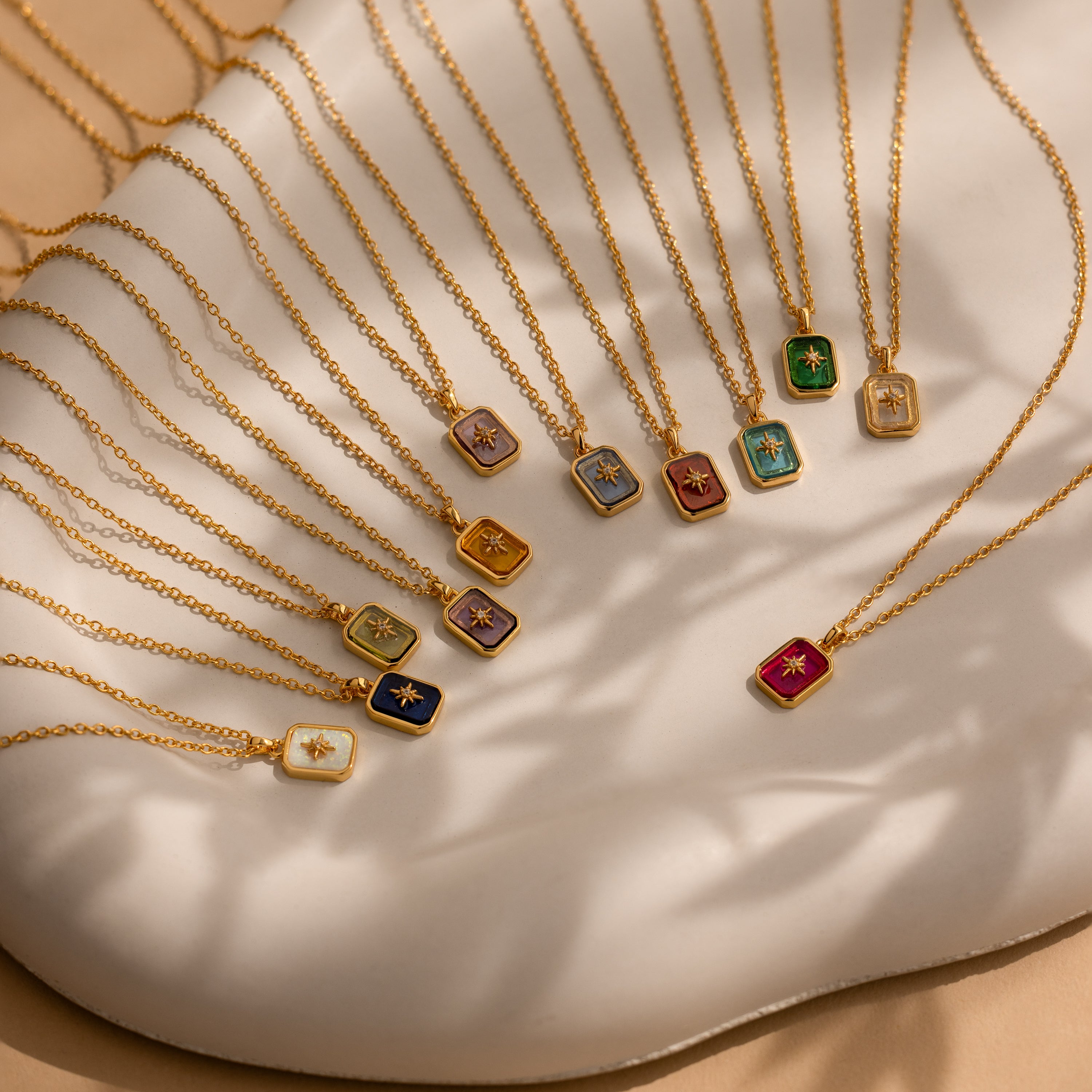 The North Star Garnet Necklace, featuring a vibrant garnet crystal pendant, is displayed on a white tray under soft, natural light.