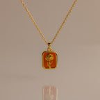 Garnet Birth Flower Charm Necklace featuring a rectangular pendant with an engraved flower design on an orange background.