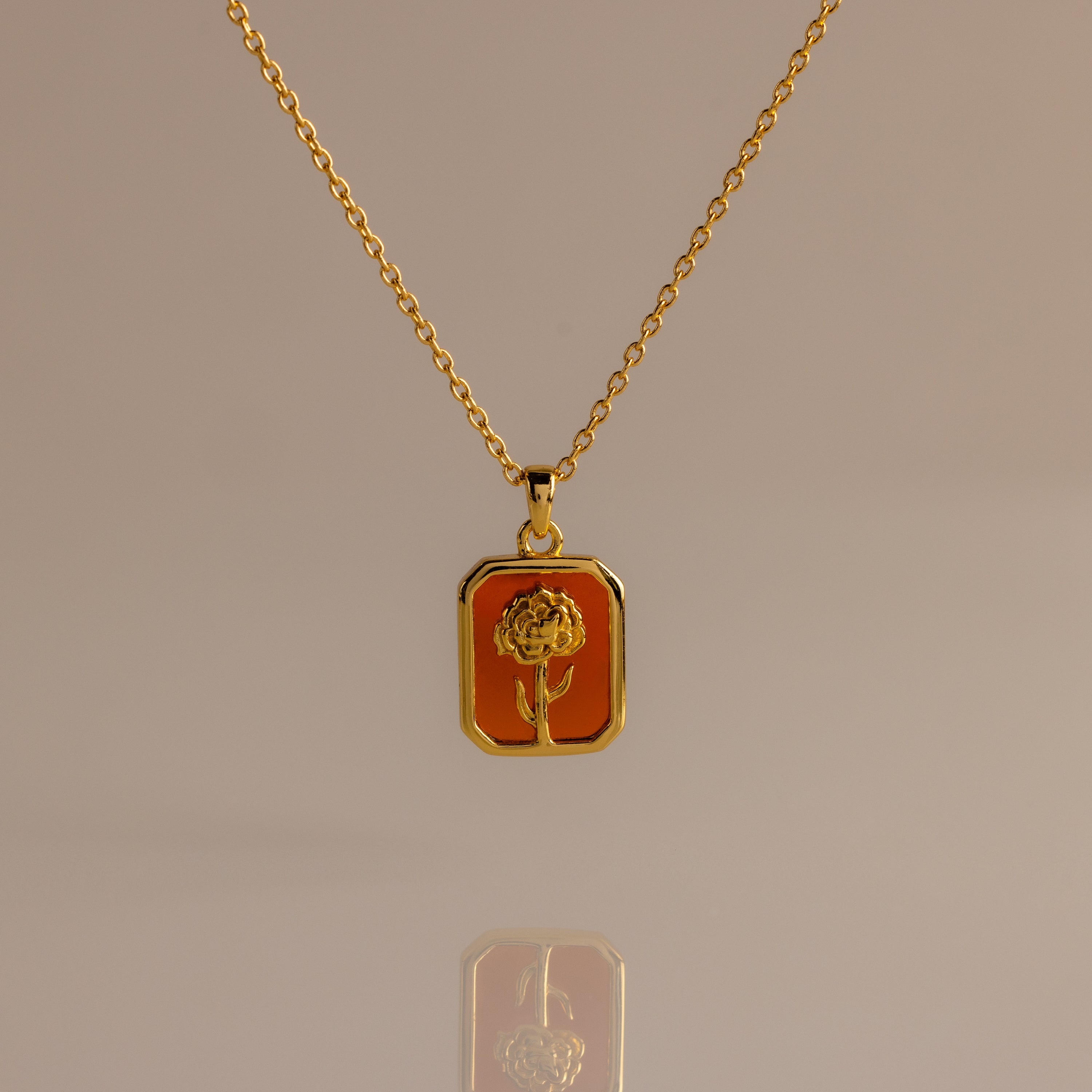 Garnet Birth Flower Charm Necklace featuring a rectangular pendant with an engraved flower design on an orange background.