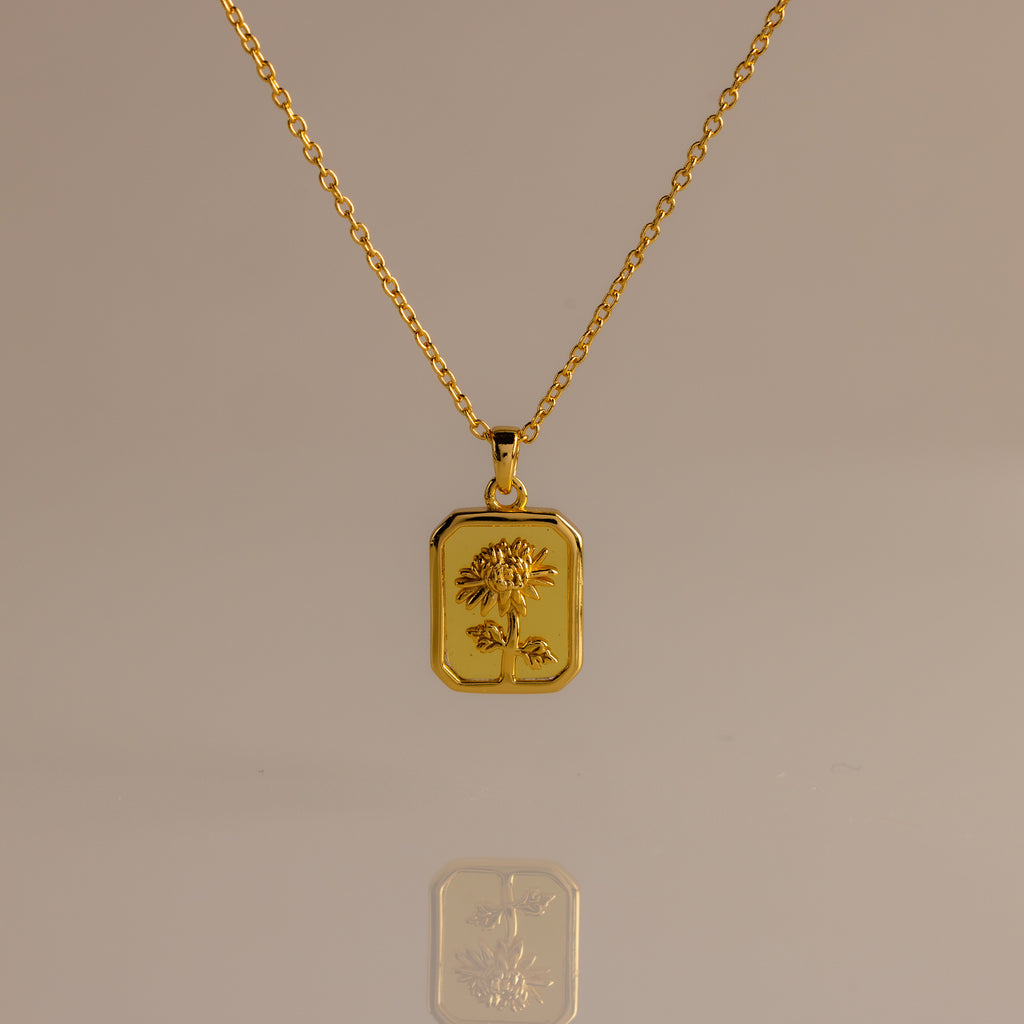 Topaz Birth Flower Charm Necklace featuring a rectangular pendant engraved with a delicate flower, displayed on a neutral background—an elegant addition to any jewelry collection.
