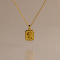 Topaz Birth Flower Charm Necklace featuring a rectangular pendant engraved with a delicate flower, displayed on a neutral background—an elegant addition to any jewelry collection.