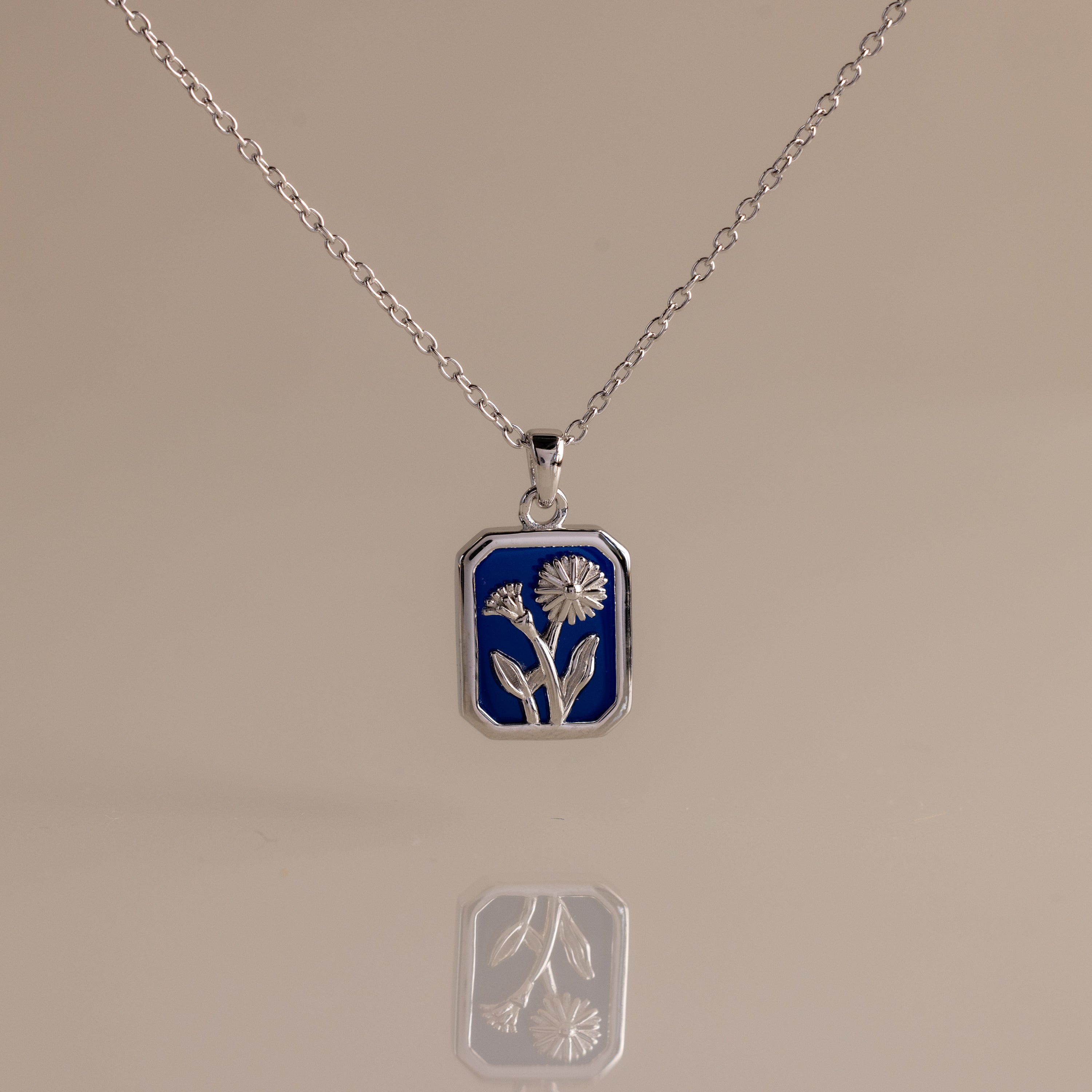 Sapphire Birth Flower Charm Necklace: Silver necklace with a blue rectangular pendant adorned with a delicate silver flower design, perfect for adding elegant style to any outfit.