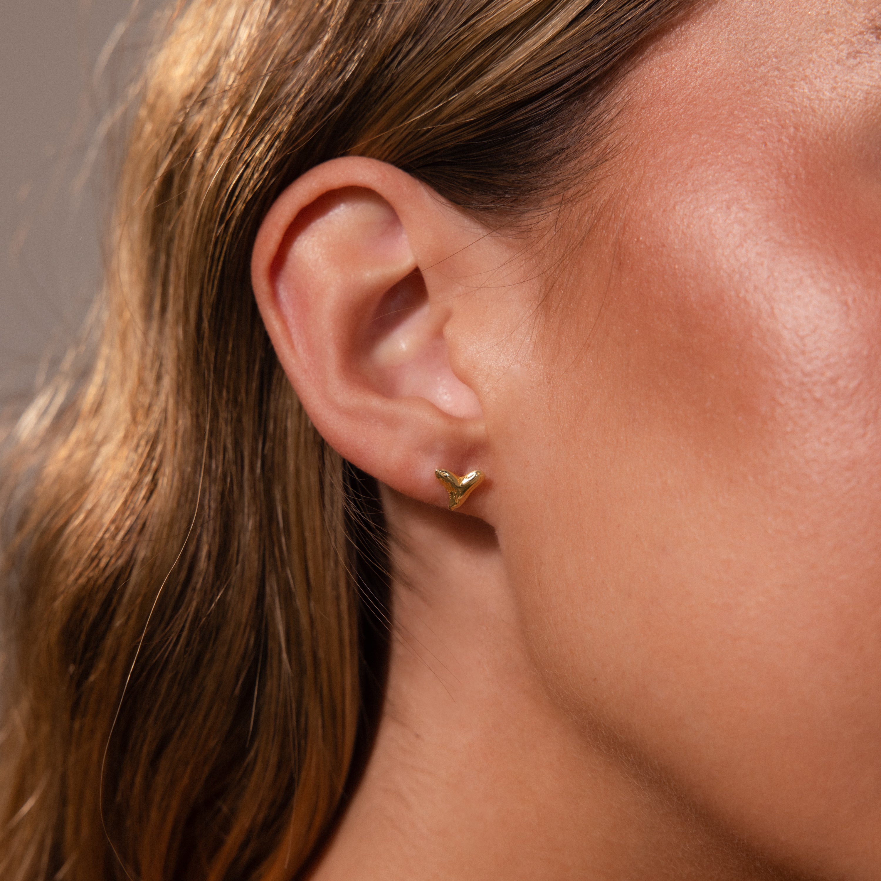 Close-up of a womans ear wearing Shark Tooth Flatback Studs in 18K Gold—perfect summer jewelry and an ideal beach-day accessory.