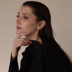 A woman with wet hair in a black top thoughtfully poses, highlighting the Marquise Diamond Climbers earrings against a neutral background.