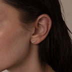 Close-up of a womans ear wearing a small, gold leaf stud earring, perfect for weddings or paired with Marquise Diamond Climbers in 18K Gold for extra elegance.