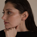 Woman with dark hair and dewy skin wearing Marquise Diamond Climbers in Silver, resting her chin on her hand and looking left.