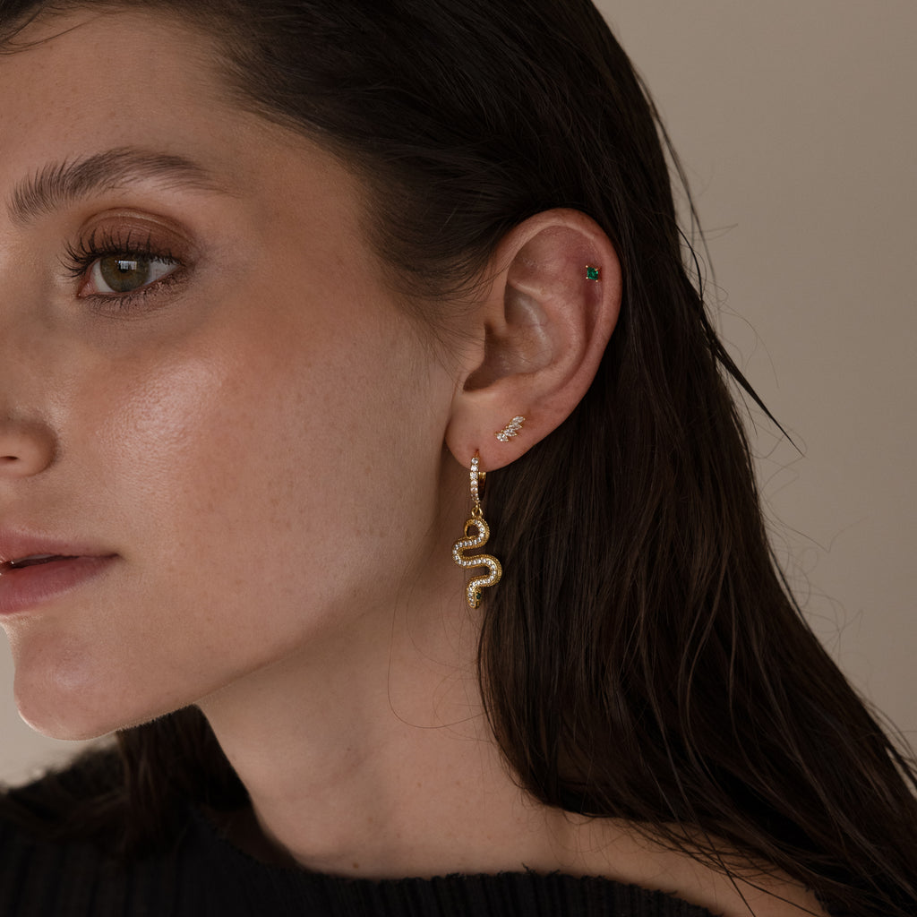 Woman with wet-look brown hair wears Marquise Diamond Climbers in 18K Gold, along with diamond studs and small ear studs.