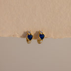 Sapphire Heart Hoops—gold earrings with blue heart-shaped stones and small clear gems—are perfect birthstone earrings to add elegance to any look.