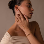 Woman in an off-shoulder top modeling gold jewelry, featuring a ring, a delicate chain bracelet, and the Turquoise Hand Chain Bracelet.