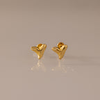 Shark Tooth Flatback Studs in 18K Gold are small, abstract chevron-shaped earrings—perfect as a summer jewelry choice, shown here on a neutral reflective surface.