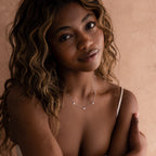 Woman with wavy hair wearing the Heart Station Necklace in Silver and a white top, posing against a neutral background.
