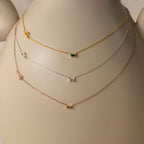The Initial Baguette Birthstone Necklace—available in gold, silver, and rose gold—is showcased on a white mannequin bust.