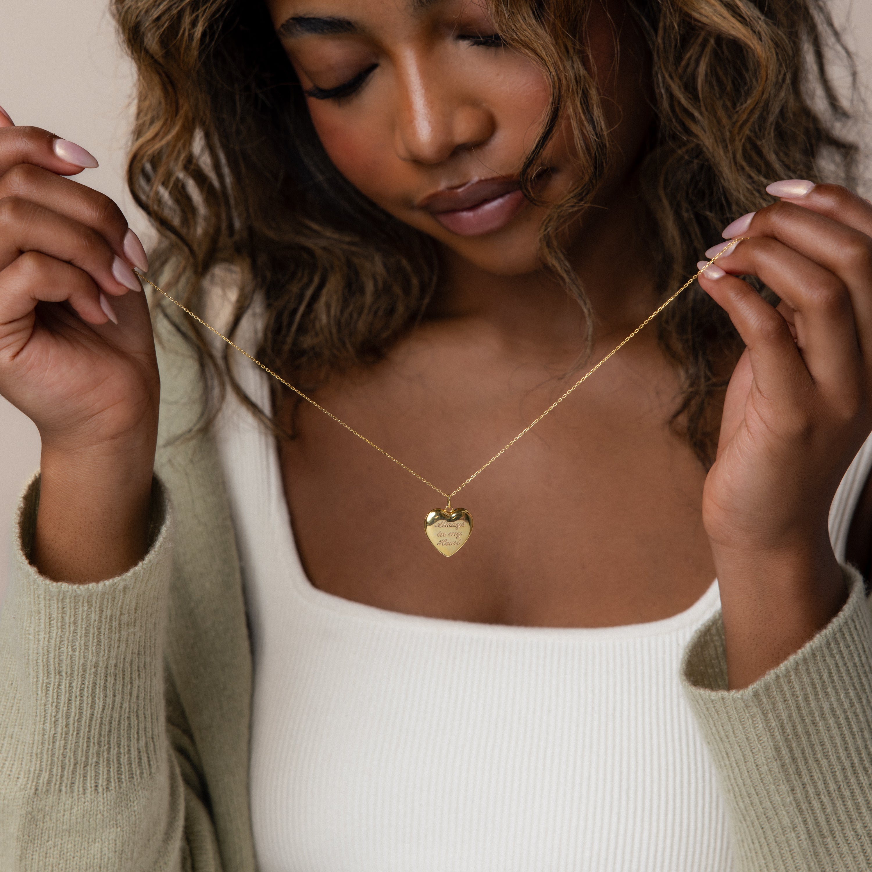 Photo of a model holding our Handwriting Heart Locket Necklace in Gold 