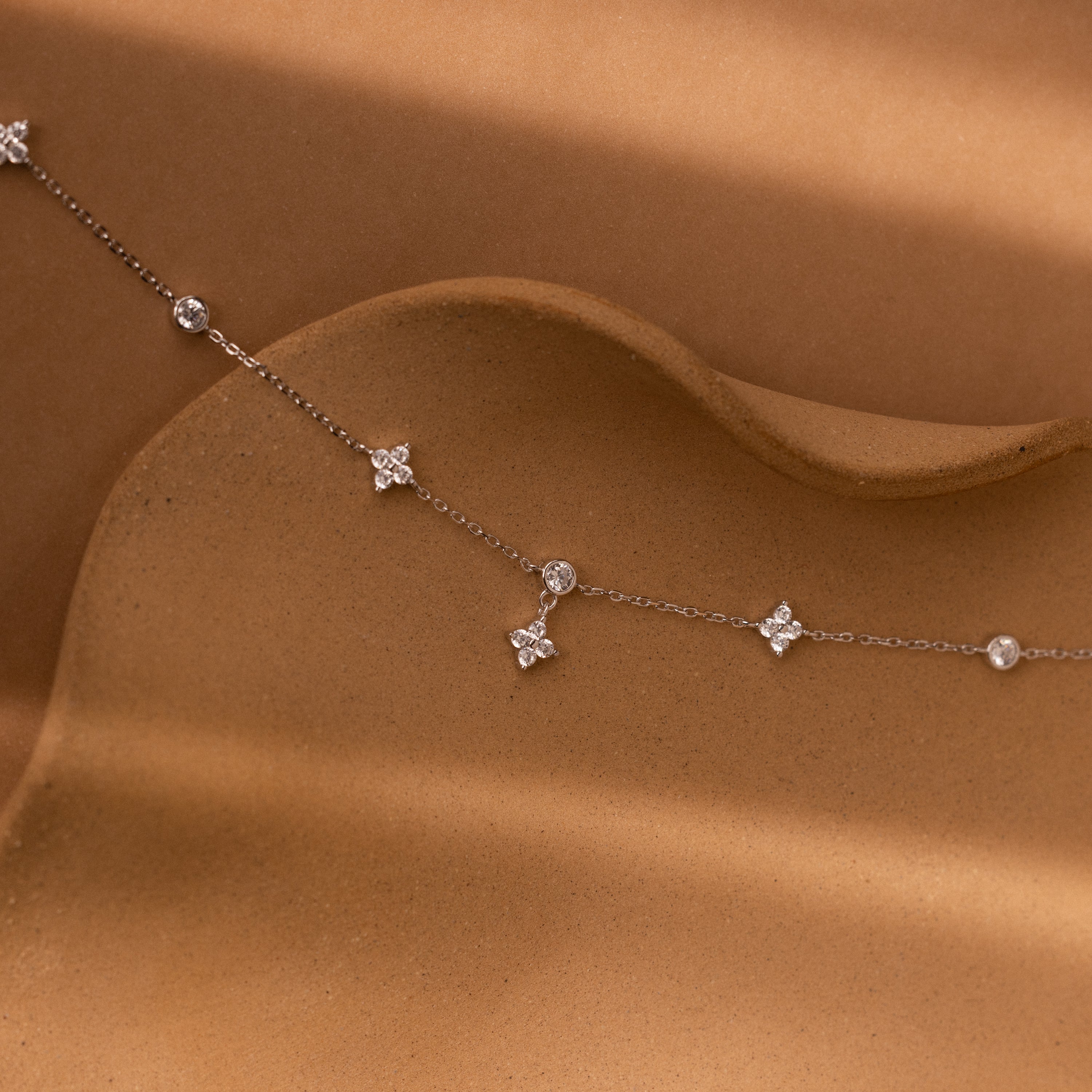 The Ivy Diamond Station Necklace in Silver features small diamond clusters with floral-inspired accents on a wavy, textured design.