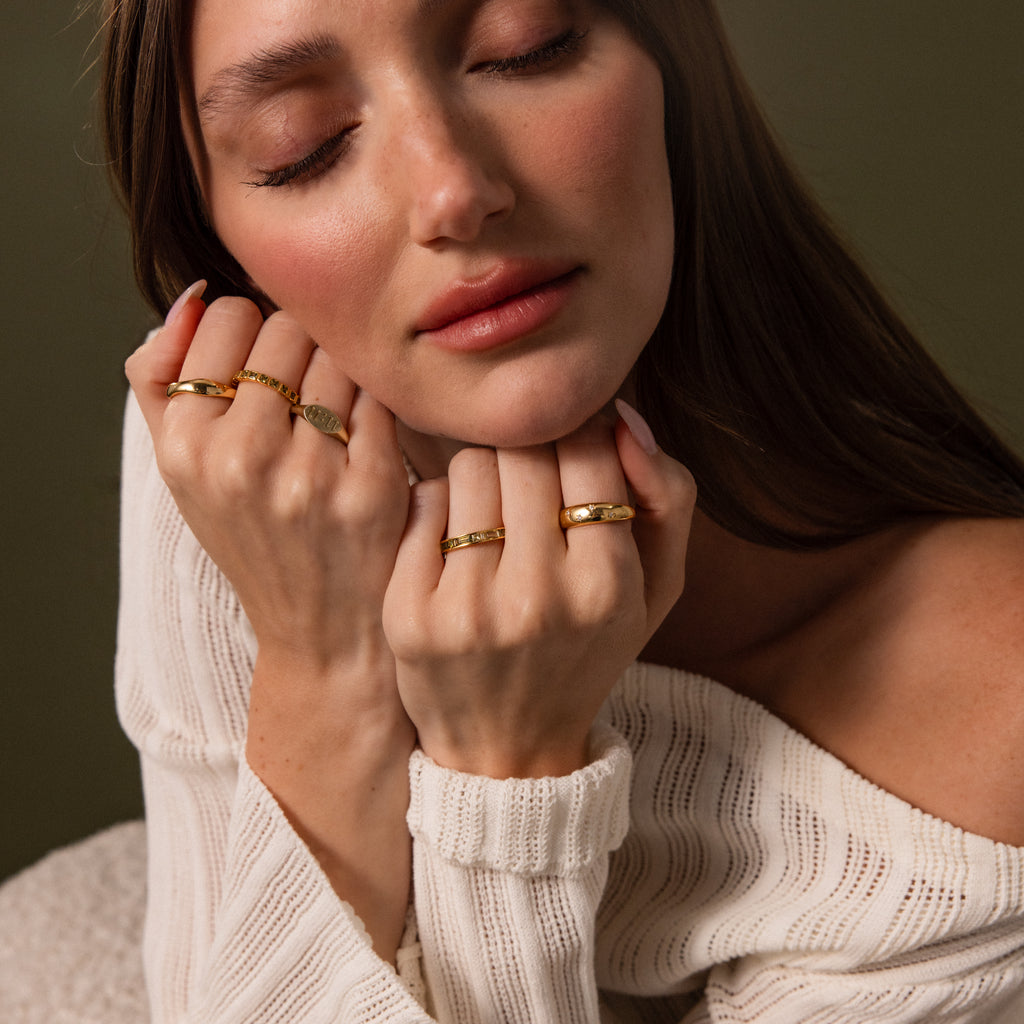 Woman with closed eyes wearing a Peridot Inlay Eternity Ring and a white off-shoulder sweater against a dark background.