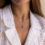 Woman wearing a white embroidered blouse and a Jade Pendant Necklace in Silver, featuring a green jade stone believed to bring luck.