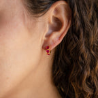 Close-up of a woman's ear wearing our Triple Amethyst Huggies—gold earrings accented with small amethyst gemstones. Part of the minimalist collection, these earrings offer customizable stones for a personal touch.