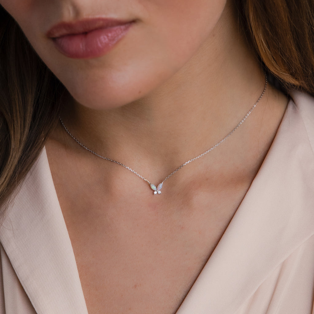 Woman wearing the Pink Opal Butterfly Necklace in Silver, featuring a delicate butterfly pendant and silver charm, paired with a light beige top.