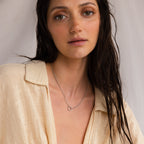 A woman with wet dark hair, dressed in a beige shirt, showcases the Rolo Circle Charm Necklace as she poses against a light background.