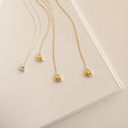 Gold and silver necklaces with lock pendants on a light beige surface