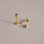 Three Dainty Garnet Flatback Studs, each gold with small garnet stones, displayed on a light beige surface—perfect lightweight earrings for multiple piercings.