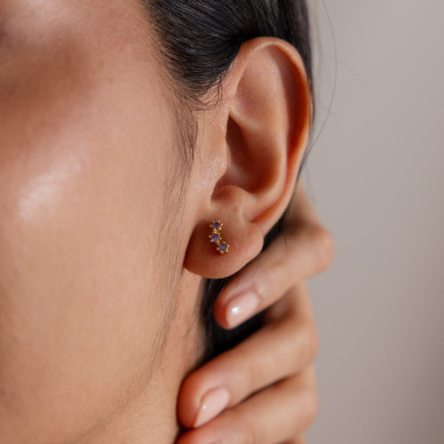 A close-up of a woman's ear wearing Topaz Cluster Flatback Studs, her hand gently resting on her neck.