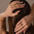 A woman with manicured nails flaunts the Sculpted Toi et Moi Ring Set in 18K Gold, her hands resting on her head as long brown hair cascades behind her.
