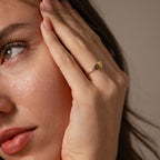 A woman touches her face while wearing the Love Toi et Moi Ring in Silver, featuring a striking yellow gemstone on her finger.