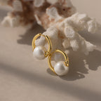 Bold Round Pearl Hoops featuring white pearls rest on white coral in gentle natural light—perfect statement earrings for every occasion.