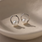Bold Round Pearl Hoops—silver hoops with white pearls—make the perfect statement earrings for any occasion. Displayed on a cream surface in soft lighting.