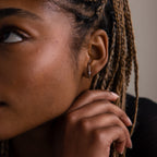 Close-up of a person with braided hair wearing a silver diamond studded ear jacket style earring.