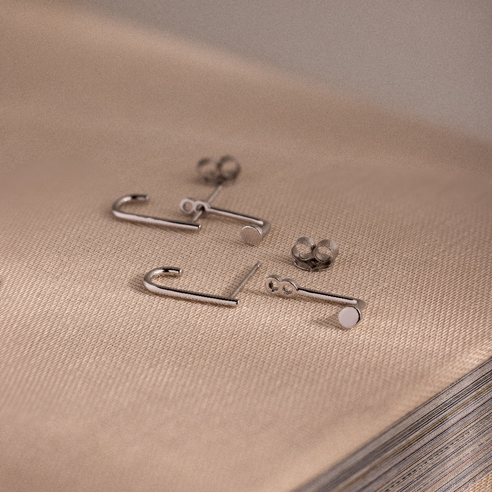 Silver jacket earrings on a textured beige surface