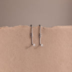 Two silver earring jackets on a beige background