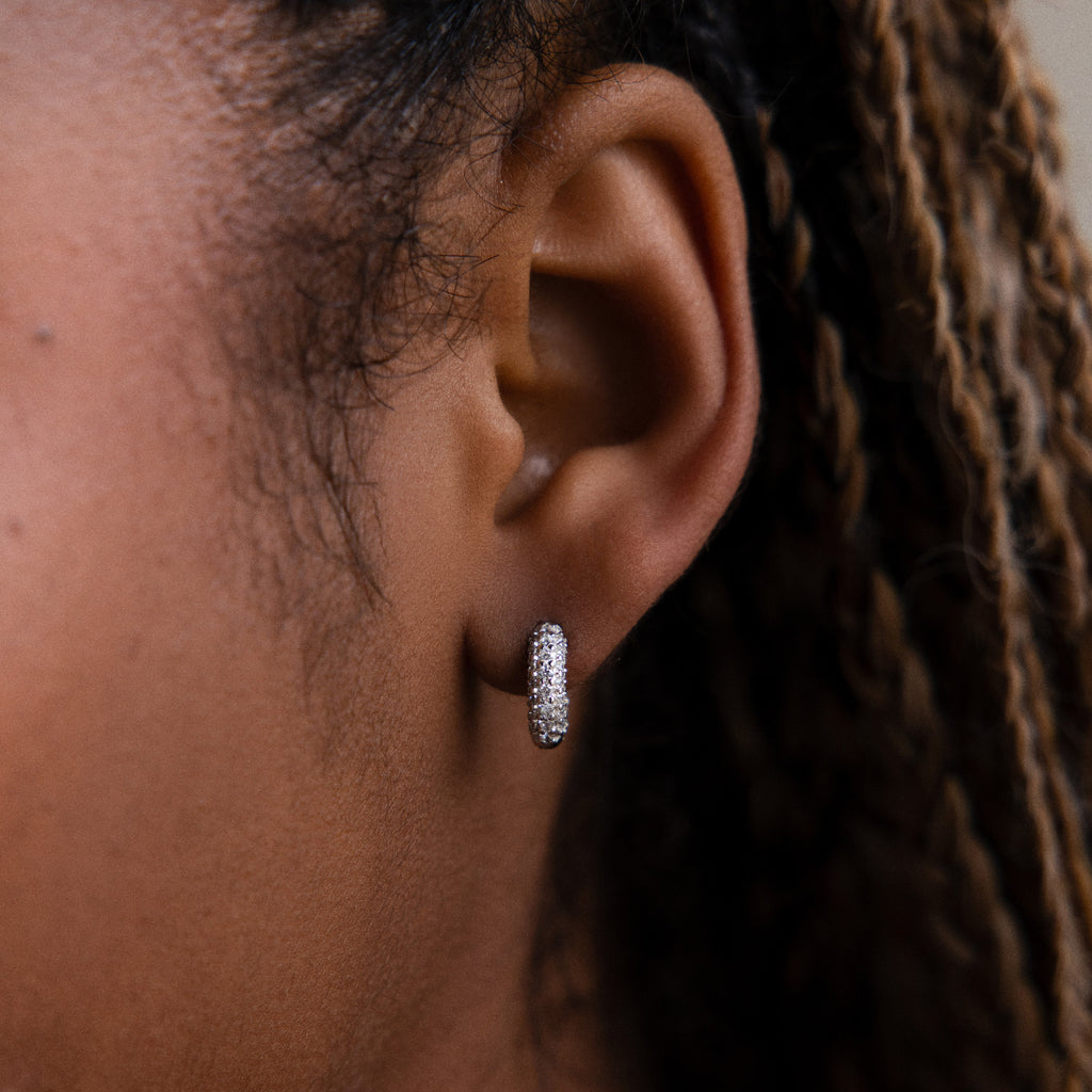 Close-up of a model wearing a diamond hoop earring with braided hair.