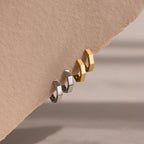 Two gold and silver hoop earrings on a beige background