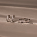 The Art Deco Diamond Earrings & Ring Set in Sterling Silver is displayed on a beige surface with soft lighting.