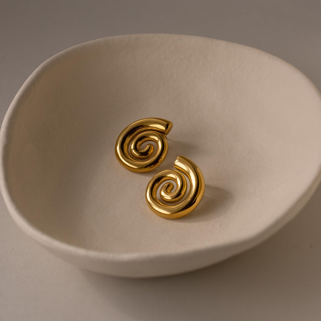 Bold Spiral Stud Earrings displayed in a round, off-white ceramic dish on a neutral background.