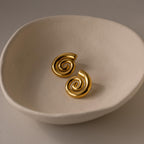 Bold Spiral Stud Earrings displayed in a round, off-white ceramic dish on a neutral background.