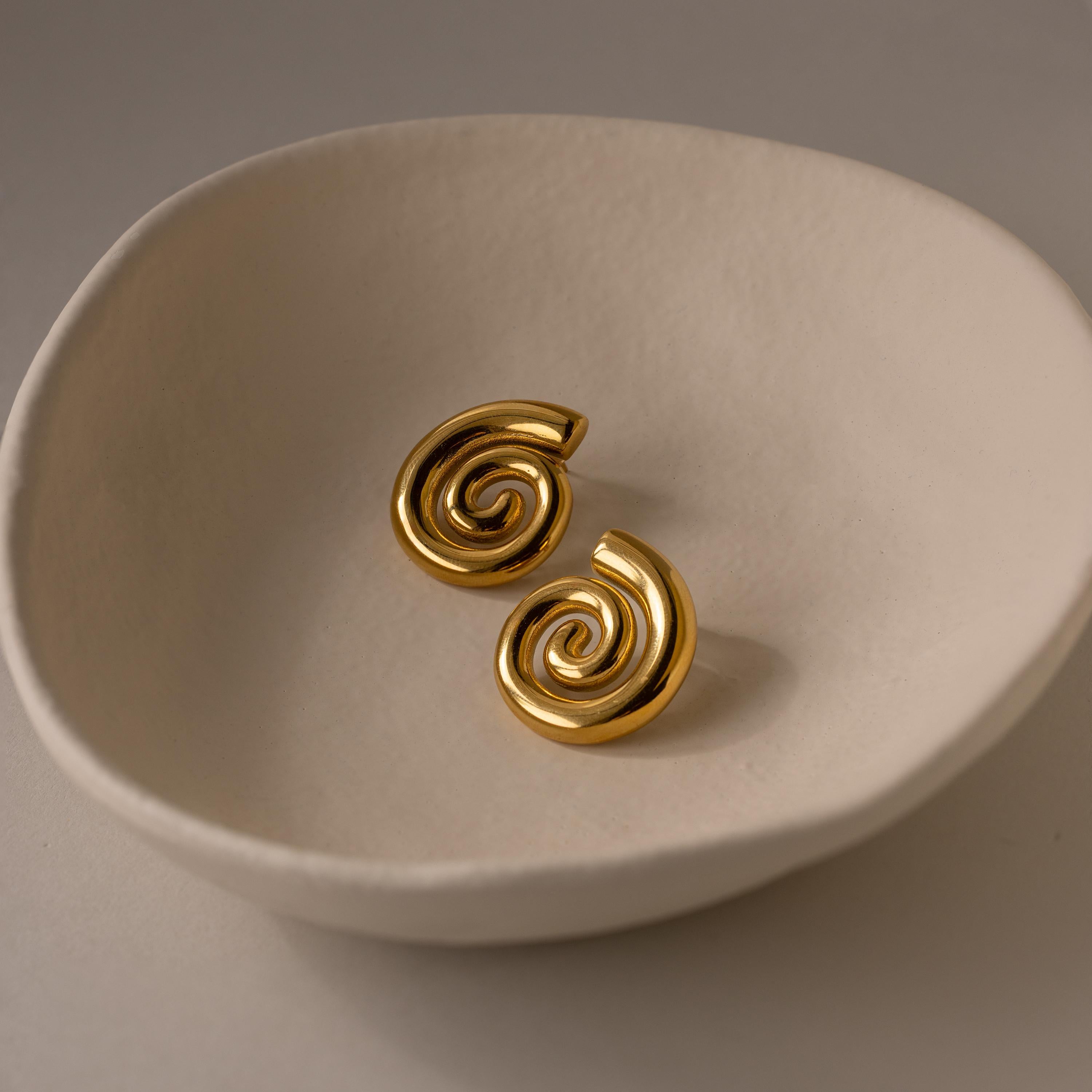 Bold Spiral Stud Earrings displayed in a round, off-white ceramic dish on a neutral background.