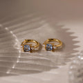 Aquamarine Pearl Huggies—gold hoop earrings with square blue gemstones and small pearls, perfect as bridal jewelry or wedding earrings—shown on a textured neutral surface.