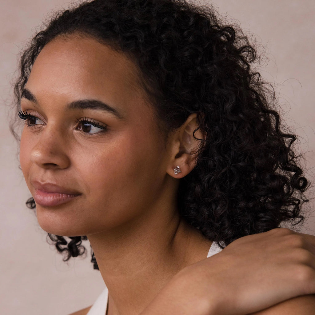 A woman with curly hair wears Beaded Herkimer Studs and gazes to the side with a gentle smile, set against a neutral background.
