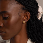 A wider side profile view of the woman wearing gold bow studs.