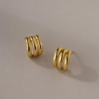Triple Loop Huggie Earrings with a gold triple-band design, ideal for everyday wear or stacking, shown on a neutral background.