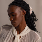 Model wearing gold pavé bow stud earrings, styled with a sheer ivory blouse and a soft neutral scrunchie, showcasing the earrings in a graceful and elegant look.